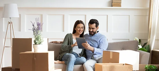 Couple sitting on their home sofa, viewing mortgage options on a tablet.